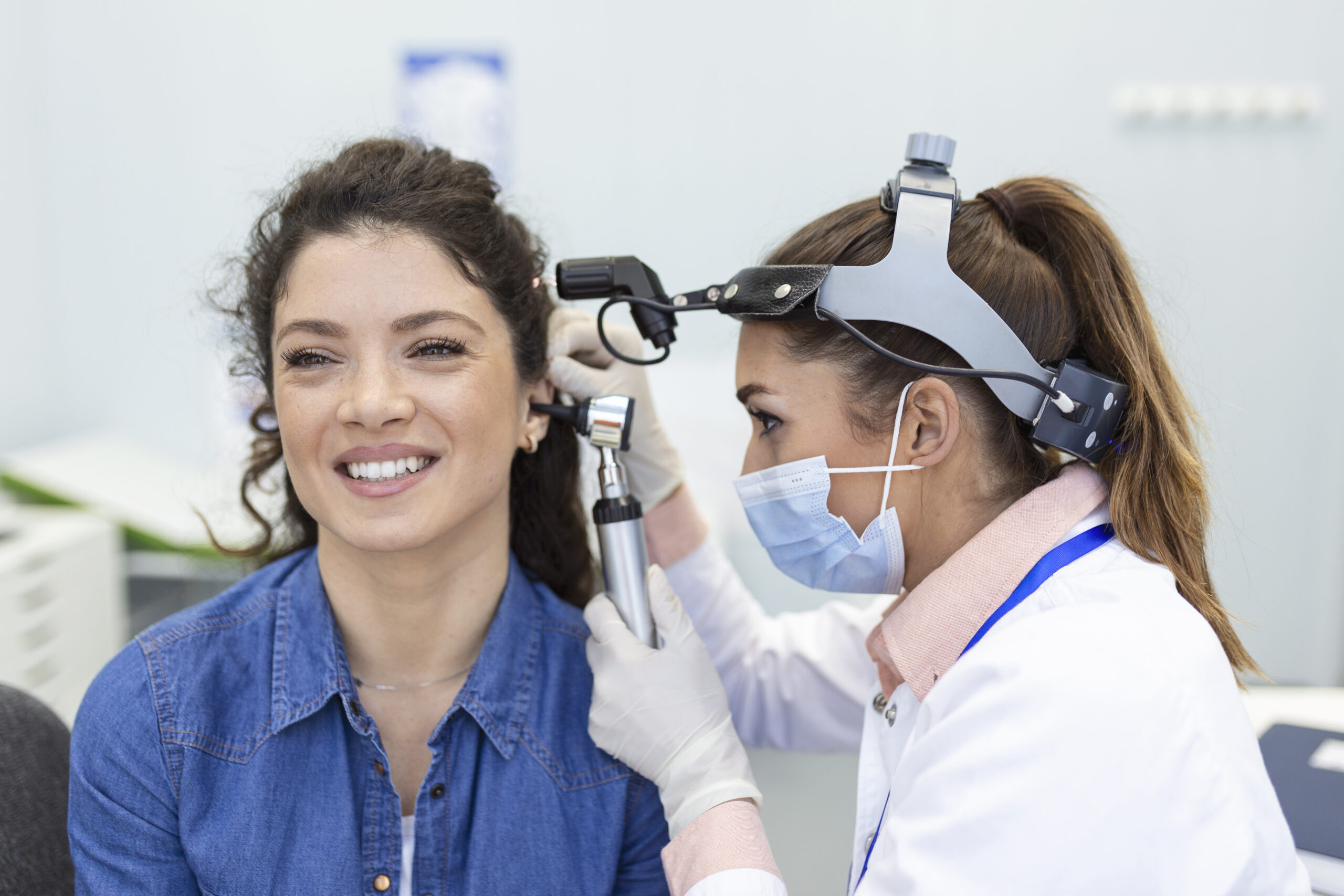 Hearing exam. Otolaryngologist doctor checking woman's ear using otoscope or auriscope at medical clinic.