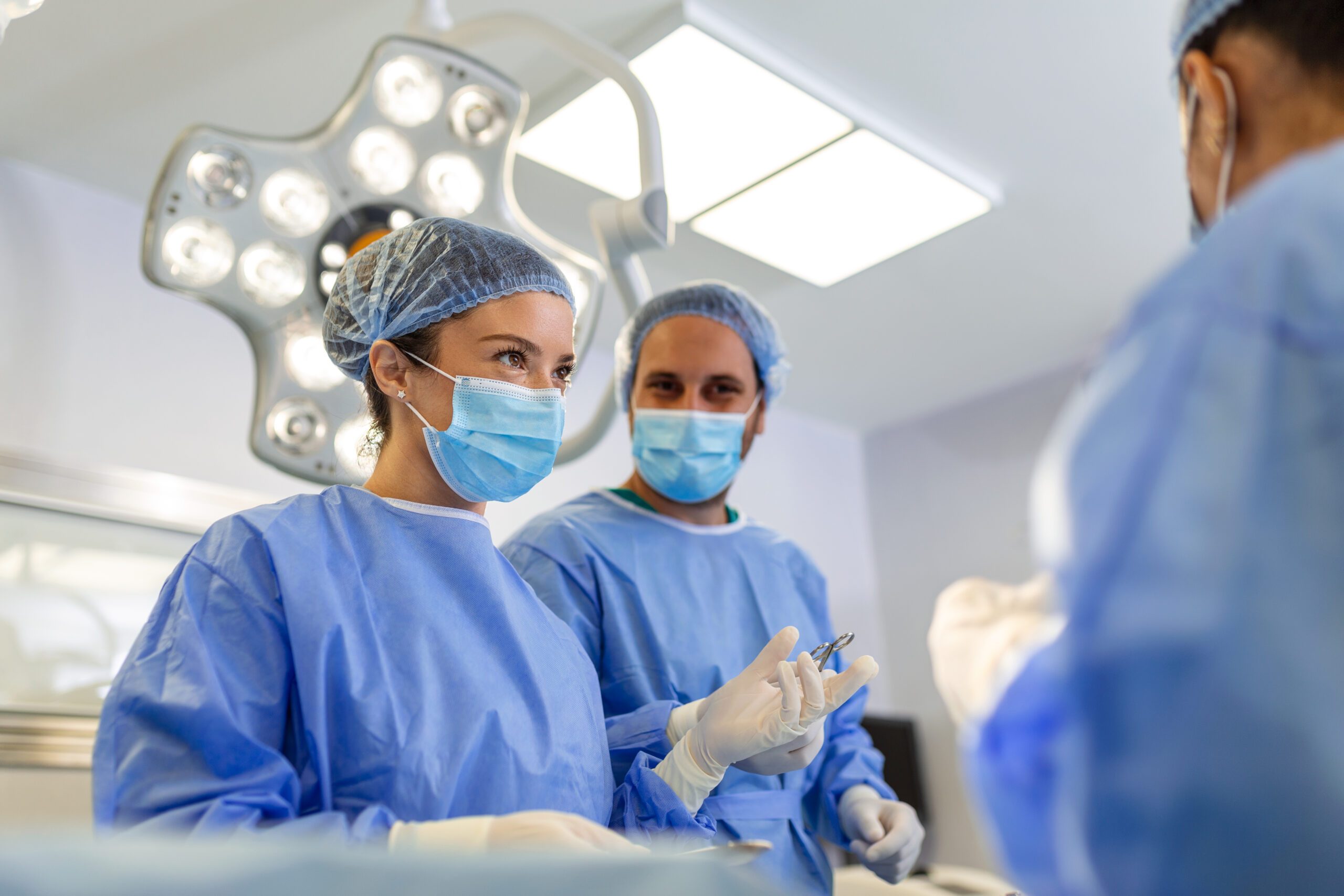 Portrait of team of multiethnic surgeons at work in a operation theatre. Several doctors surrounding patient on operation table during their work. Team surgeons at work in operating room.