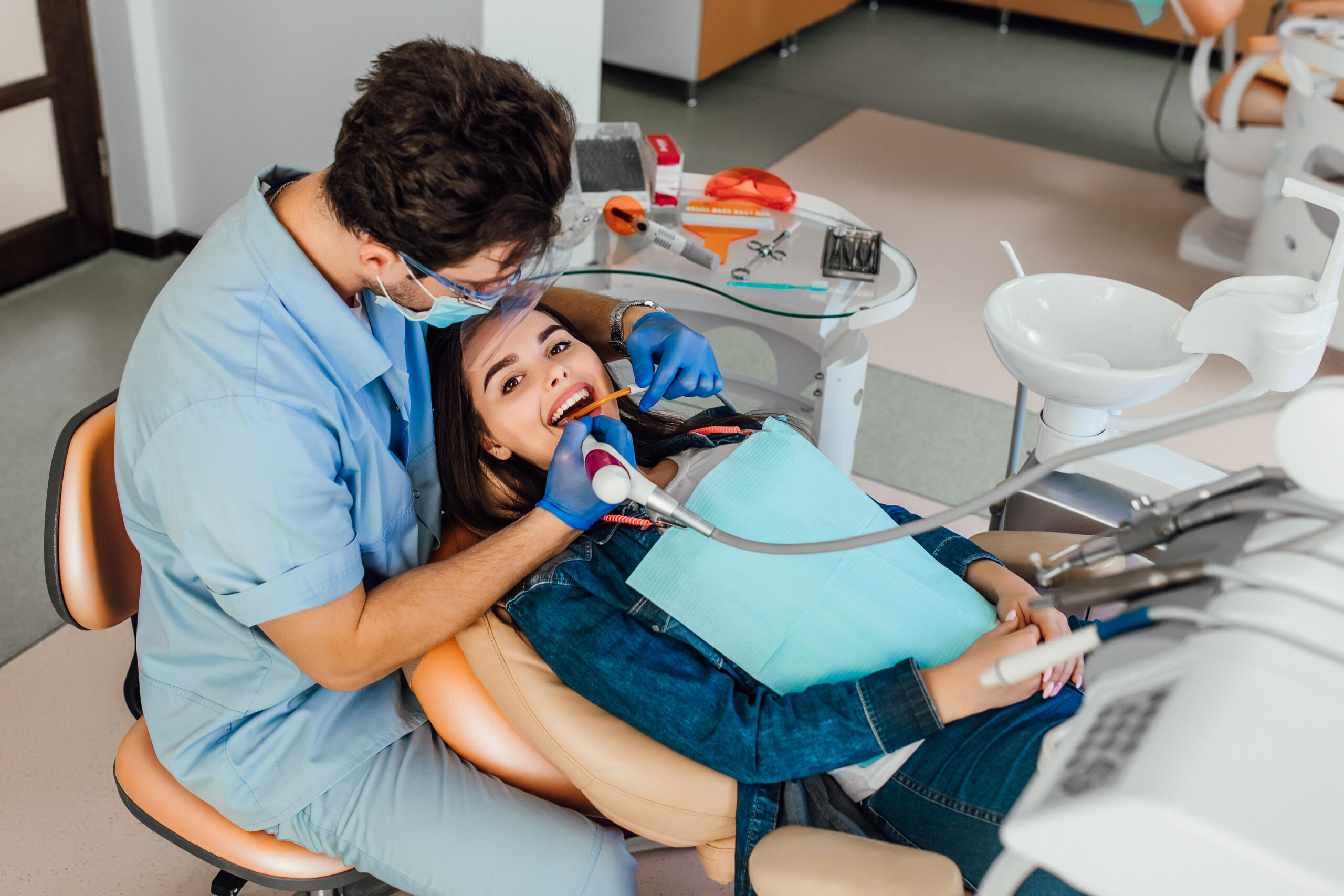 Young female patient with open mouth examining dental inspection at dentist office.